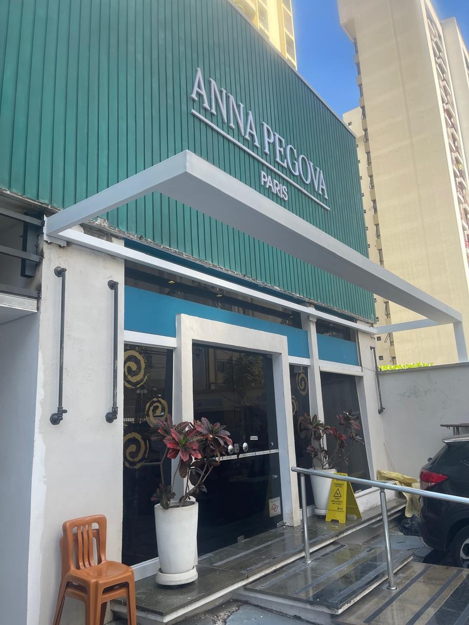 Detalhe da cobertura metálica branca integrada à entrada comercial